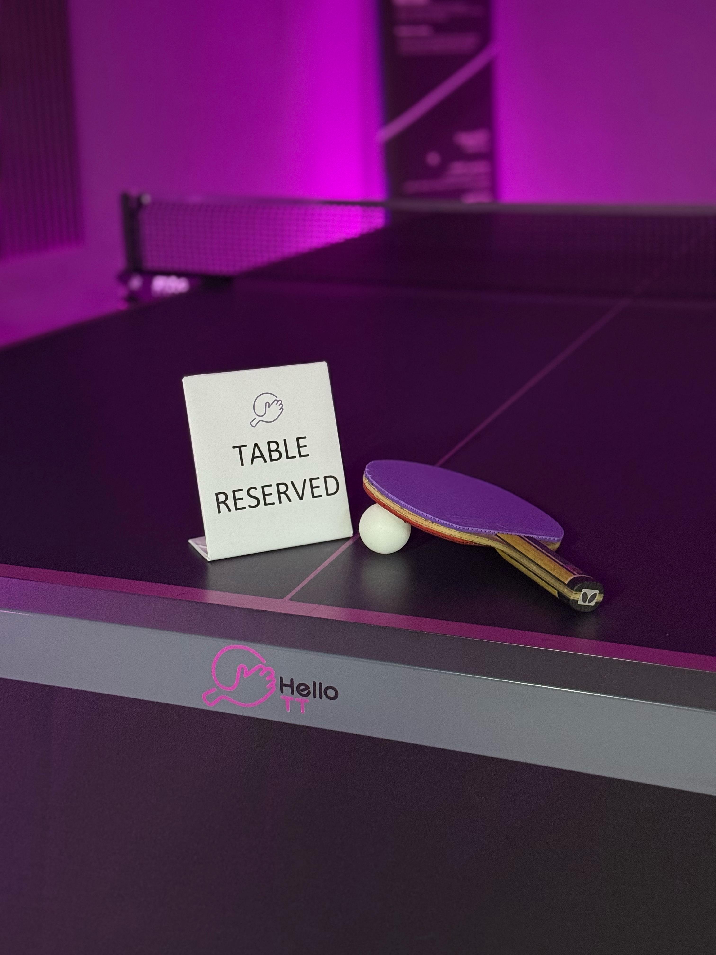 A HelloTT table marked reserved with a paddle and ball