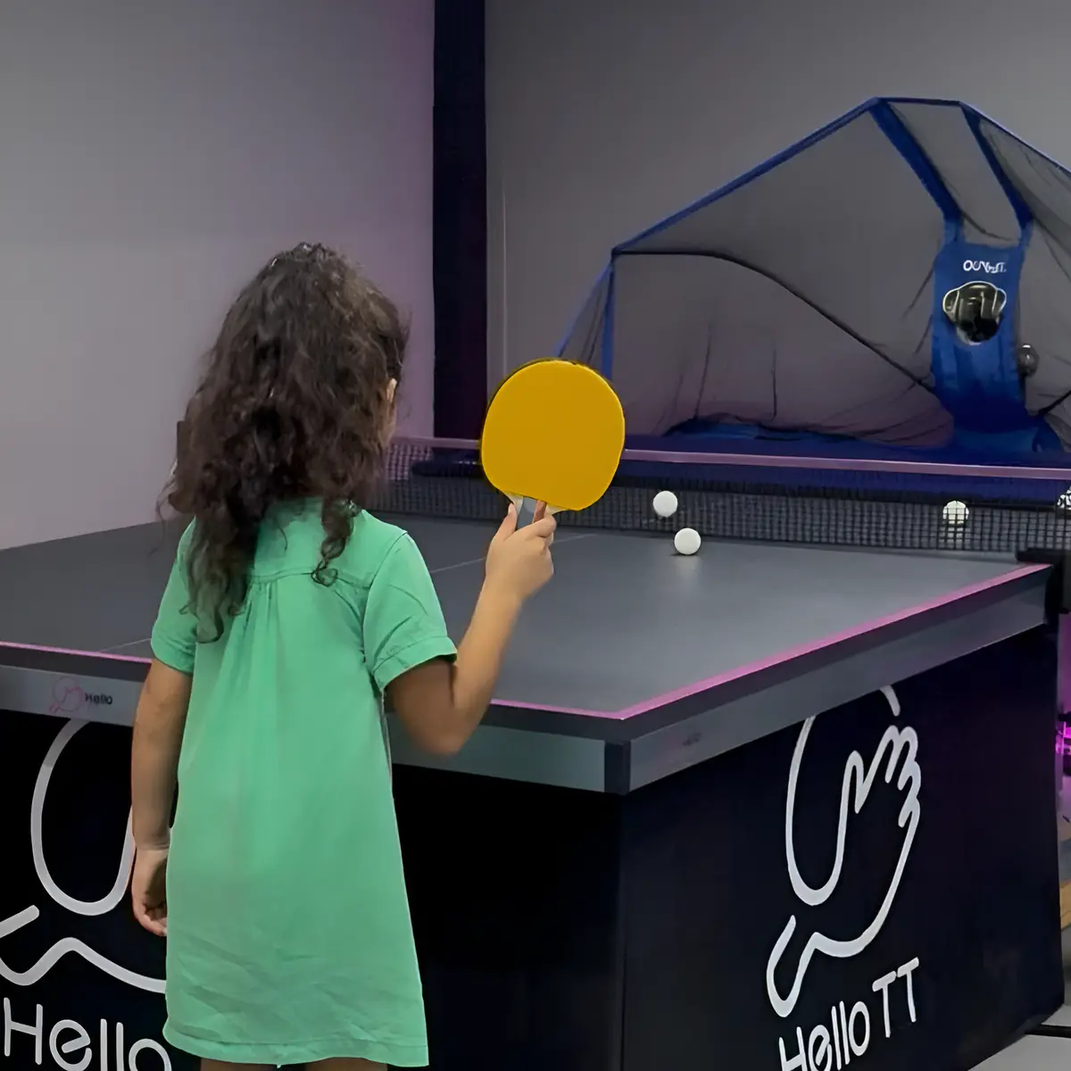 A child playing against the table tennis robot