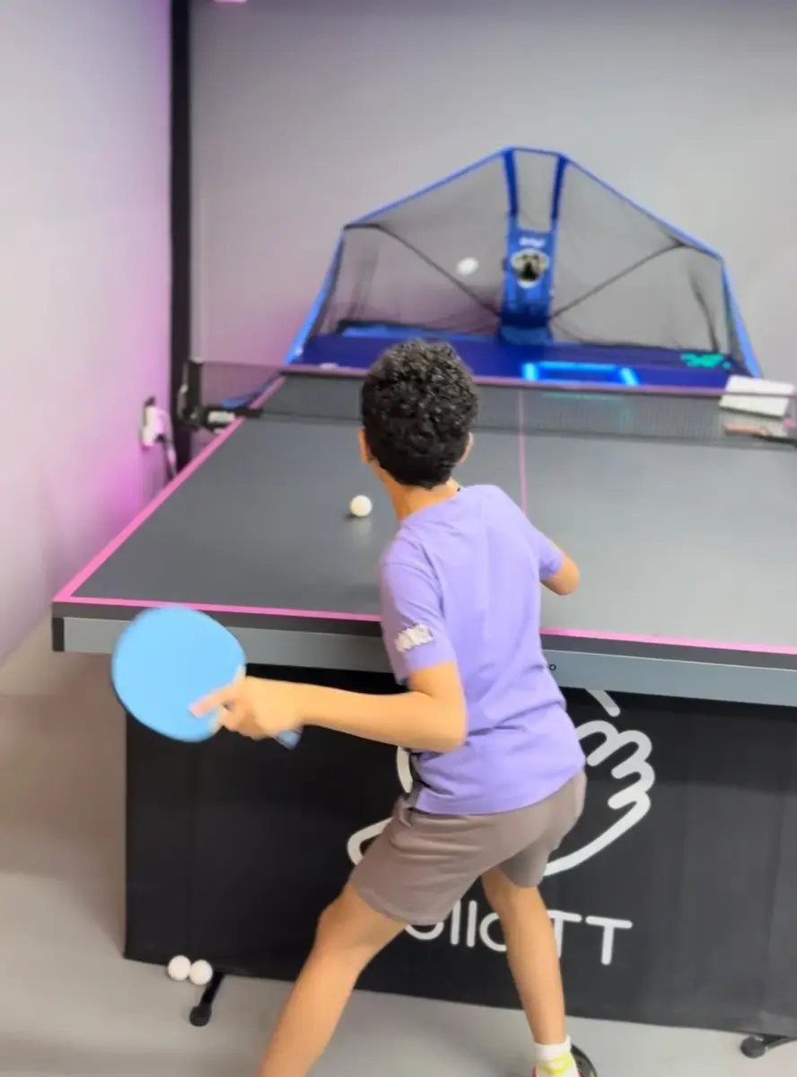 A beginner learning a forehand against the robot